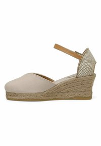 Beige canvas wedge sandaal met een espadrille wikkel, enkelbandje en gestreept, textuurpatroon achterpaneel. Heeft een ronde neus en een platte rubberen zool.