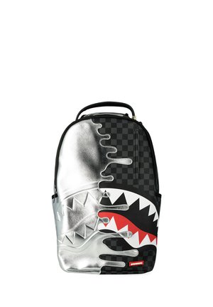 Zaino con motivo a scacchiera nera e pannello argentato metallico con design di bocca di squalo rossa e bianca con denti affilati.