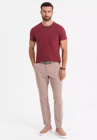 Pánský outfit obsahující burgundské bavlněné tričko, béžové kalhoty v slim fit a světlé nazouvací boty. Akcenty texturované tkaniny.