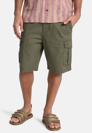 Olivgrüne Cargo-Shorts mit Seitentaschen, aus strapazierfähigem Stoff gefertigt. Kombiniert mit braunen Sandalen mit mehreren Riemen.