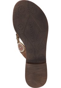 Semelle de sandale marron présentant un caoutchouc texturé avec des motifs floraux, un design tissé et des accents décoratifs en perles près de la bride.