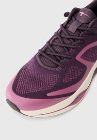 Scarpa sportiva in tonalità di viola e rosa, con una tomaia in rete traspirante, chiusura con lacci, superficie texture e suola ammortizzata.
