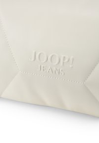Biela kožená taška s textúrovaným povrchom, s embosovaným logom "JOOP! JEANS" a geometrickým vzorom prešívania. Hladký povrch a jemný lesk.