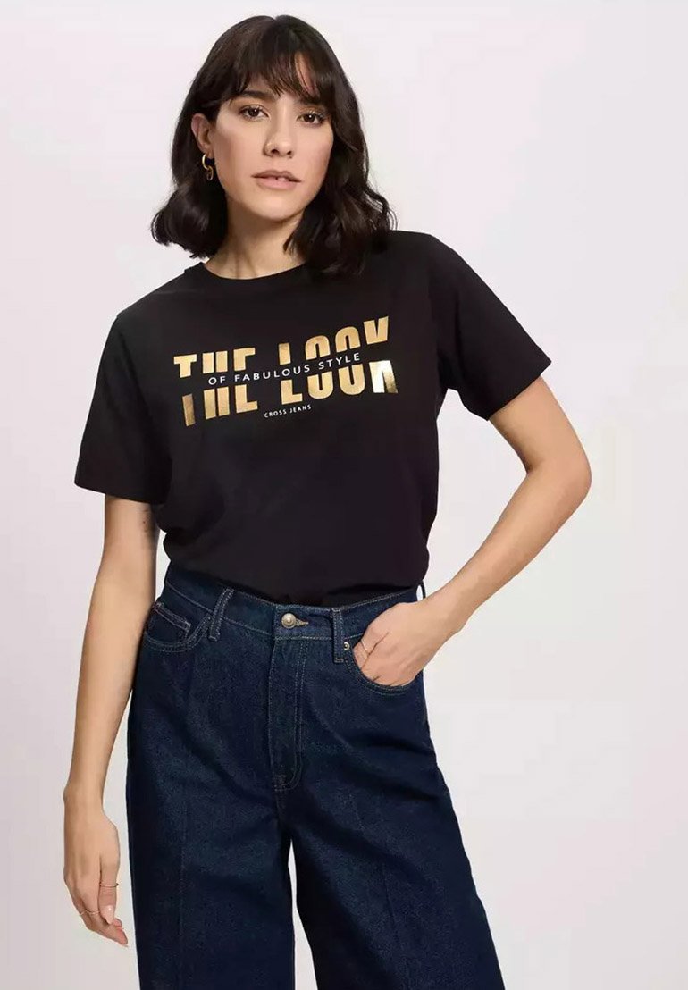 Czarny bawełniany t-shirt z złotym nadrukiem "WYGLĄD FENOMENALNEGO STYLU" w luźnym kroju. W parze z niebieskimi dżinsami o wysokim stanie.