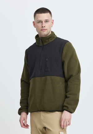 Sudadera de forro polar en verde oliva con un panel negro en el pecho, cierre de media cremallera y bolsillo con cremallera en el lado izquierdo. Textura suave.
