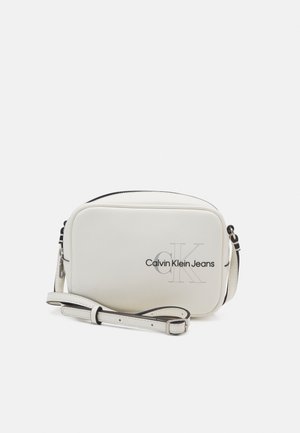 Bílá obdélníková crossbody taška Calvin Klein Jeans s nastavitelným popruhem a černým logem na přední straně.