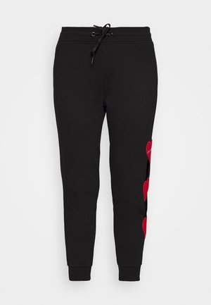 Sorte joggebukser med elastisk talje og snøre, der har tre røde hjertepatches langs det ene ben.