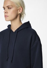Felpa in cotone blu navy con cappuccio regolabile, vestibilità comoda e texture morbida. Presenta maniche lunghe e un design semplice senza loghi.