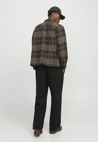 Jachetă carosată în nuanțe închise, cu accente roșii și verzi. Croială lejeră, guler cu nasturi și buzunare laterale. Asortată cu pantaloni negri.