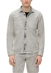 Lichtgrijze denimjas met twee borstzakken, knoopsluiting en een licht vervaagde uitstraling. Lange mouwen en een puntige kraag.