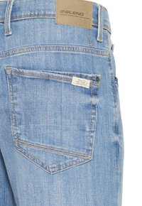 Hellblaue Denim-Jeans mit einem Leder-Rückenpatch, klassischem Taschen-Design und einem kleinen Etikett an der Hintertasche.