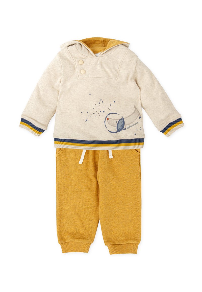 Sudadera con capucha en beige claro con acentos en azul oscuro y amarillo, que presenta un gráfico de un telescopio. Combinada con pantalones de ch�ándal de color mostaza.