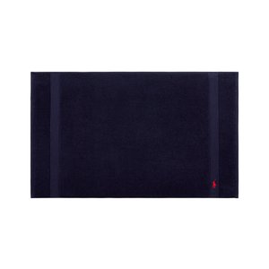 Μπάνιο χαλάκι από βαμβάκι σε ναυτικό μπλε χρώμα με υφή, που διαθέτει δύο κάθετες ρίγες και ένα μικρό κόκκινο λογότυπο σε μια γωνία.