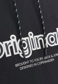 Sudadera negra con texto blanco que dice "Original" y un texto más pequeño debajo. Cuenta con cordones en blanco y negro y una textura suave.