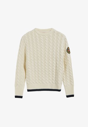 Maglione color crema con design a trecce, scollatura rotonda, polsini e orlo a coste, con un accento a strisce blu navy nella parte inferiore e una patch ricamata.