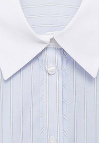 Camicia a righe blu e bianche con colletto bianco, dotata di chiusura a bottoni e righe verticali. Tessuto liscio con dettagli sottili.