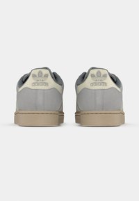 Sneakers in camoscio grigio con dettagli beige, punta tonda, suola piatta in gomma e logo in rilievo sul tallone. Design classico a taglio basso.