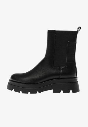 Bottine en cuir noir avec semelle robuste à crampons, panneau latéral élastique et languette à l'arrière pour un enfilage facile.