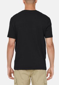Sort kortærmet T-shirt med lige kant og rund halsudskæring. Stoffet fremstår glat med en normal pasform, båret over khaki cargo-bukser.