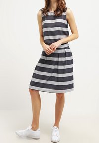 Vestido sin mangas a rayas en azul marino y blanco, con un top ajustado y una falda acampanada. Hecho de tela suave, cuenta con un diseño transpirable.