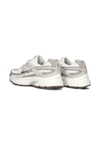 White and light gray athletic shoes with mesh and synthetic material, featuring a textured sole, rounded shape, and subtle accents.