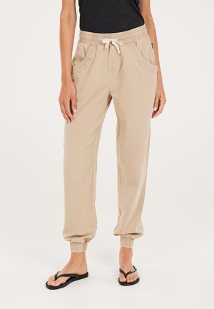 Pantaloni in lino leggeri di colore beige con vita elastica, cordoncino e doppie tasche frontali. I polsini alla caviglia creano una vestibilità affusolata.