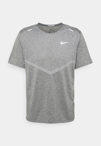 Camiseta de manga corta Dri-FIT gris de Nike con un tejido texturizado, que presenta un sutil patrón en forma de chevron y un logo blanco en el lado izquierdo del pecho.