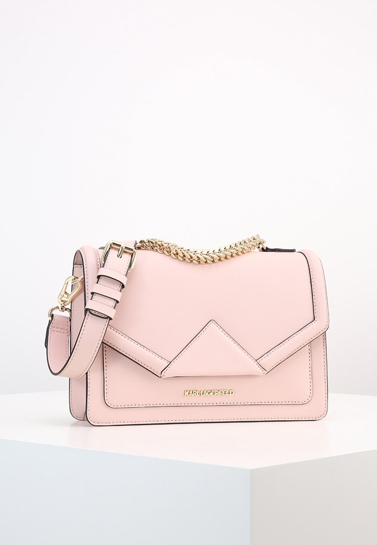 Sac à main rectangulaire en cuir rose clair avec bandoulière chaîne dorée et logo Karl Lagerfeld sur le devant, exposé sur une surface blanche.