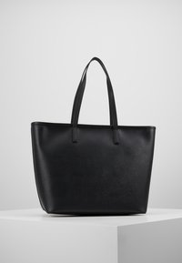 Zwarte leren tote bag met een soepele textuur, rechthoekige vorm, dubbele handvatten aan de bovenkant en subtiele stikdetails. Geen externe zakken.