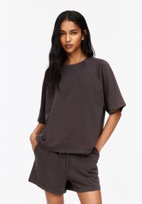Donkergrijze oversized t-shirt met korte mouwen en een ronde halslijn, gecombineerd met bijpassende shorts. Zacht materiaal, casual pasvorm, minimalistisch ontwerp.