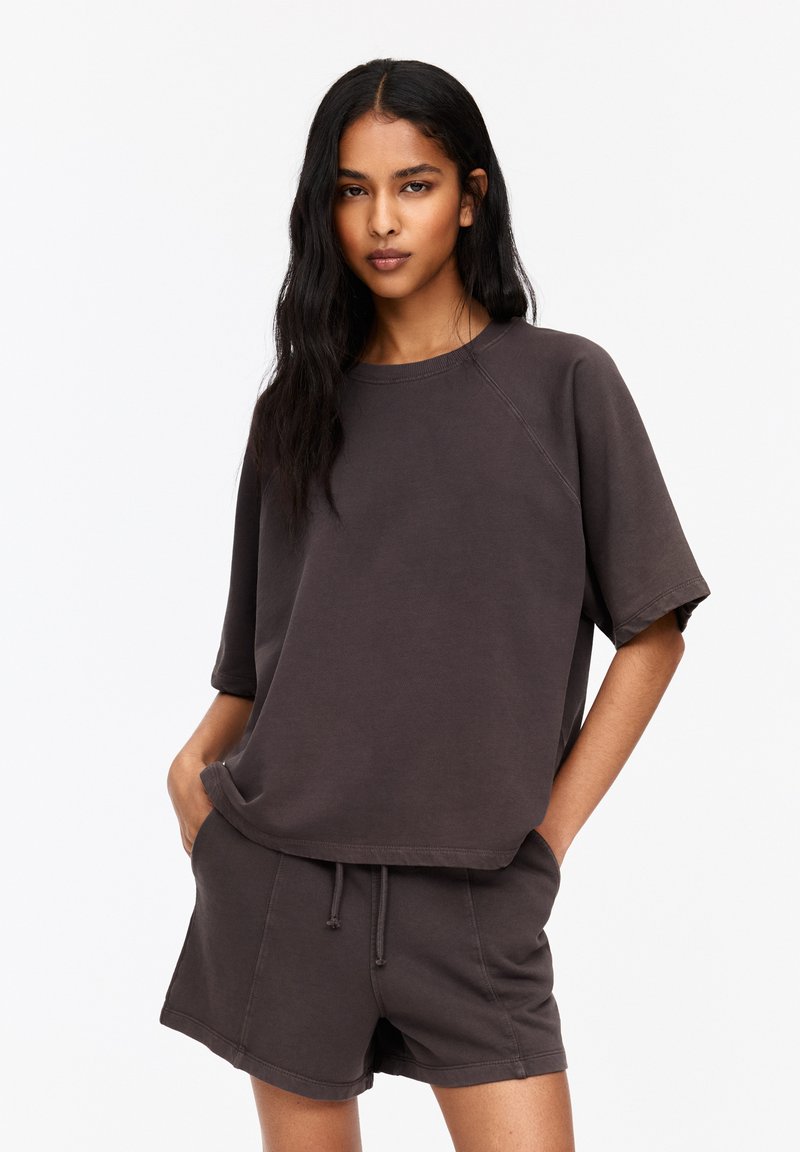 Donkergrijze oversized t-shirt met korte mouwen en een ronde halslijn, gecombineerd met bijpassende shorts. Zacht materiaal, casual pasvorm, minimalistisch ontwerp.