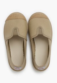 Baskets slip-on en toile beige avec un embout tissé texturé de couleur tan. Forme arrondie, talon enveloppé et un design simple avec des coutures.