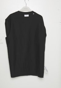 Tricou negru cu mânecă scurtă și croială lejeră. Material din bumbac moale, cusături plate și etichetă la gât. Se află pe un umeraș din plastic alb, pe un fundal deschis.