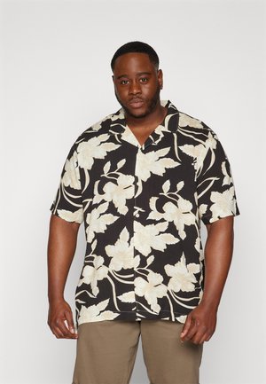 Short-sleeve black shirt with large beige floral pattern and a button-up design, paired with light beige trousers.