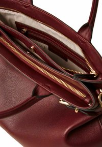 Borsa in pelle borgogna con finitura texturizzata, dotata di cerniere dorate e molteplici scomparti, inclusa una tasca con zip e fodera interna.