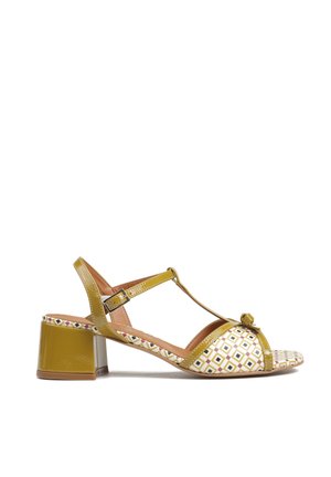 Damski sandał na obcasie typu słupek, w kolorze musztardowej żółci, z paskami, geometrycznym wzorem z przodu i klamrą wokół kostki.