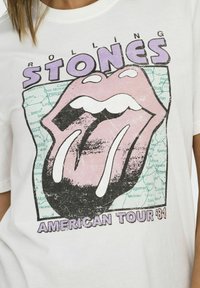 Hvid bomulds t-shirt med et vintage Rolling Stones grafik. Designet inkluderer en pink tunge og teksten "American Tour '81" i lilla.