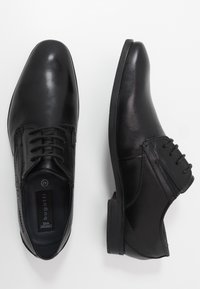 Chaussures habillées en cuir noir avec une finition lisse, un embout arrondi et un design à lacets avec des accents texturés sur les côtés. Semelle plate et durable.