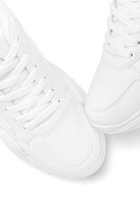 White sneakers made of smooth leather with rounded toe and textured tongue. Features flat laces and a cushioned sole for comfort.