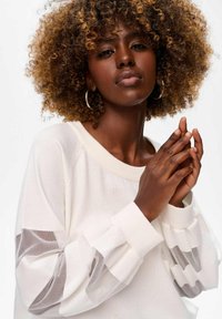 Lichtcrème trui met doorschijnende, gestreepte mesh-mouwen en geribbelde manchetten. Het ontwerp heeft een brede halslijn en een gestructureerde stof.