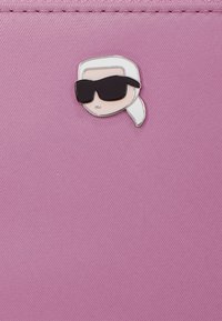 Enamel pin featuring a cartoon face with white hair and black sunglasses on a textured pink surface.
