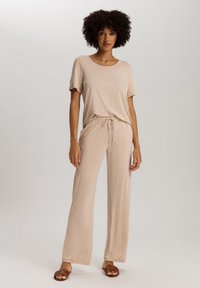 Beige lounge-outfit bestaande uit een T-shirt met korte mouwen en losse, met een trekkoord verstelbare broek. Zachte stof met een lichte textuur en een relaxte pasvorm.
