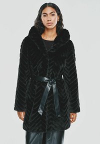 Czarny płaszcz z sztucznego futra z wzorem w zygzak, dużym kołnierzem i błyszczącym czarnym paskiem. Długie rękawy o luźnym kroju.