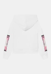 Sudadera blanca con capucha y estampados abstractos rectangulares en rosa y negro en ambas mangas, vista desde la parte posterior.