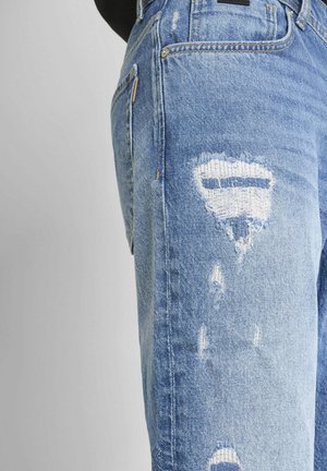 Svijetloplave izlizane traperice imaju razderane rupe, klasičan dizajn s pet džepova i ispucalu boju koja daje teksturirani izgled.