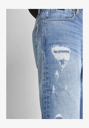 Svijetloplave izlizane traperice imaju razderane rupe, klasičan dizajn s pet džepova i ispucalu boju koja daje teksturirani izgled.