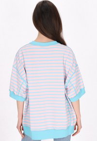 Överdimensionerad t-shirt med rosa och blå ränder, korta ärmar, en blå halsringning och en mjuk tygliknande textur.