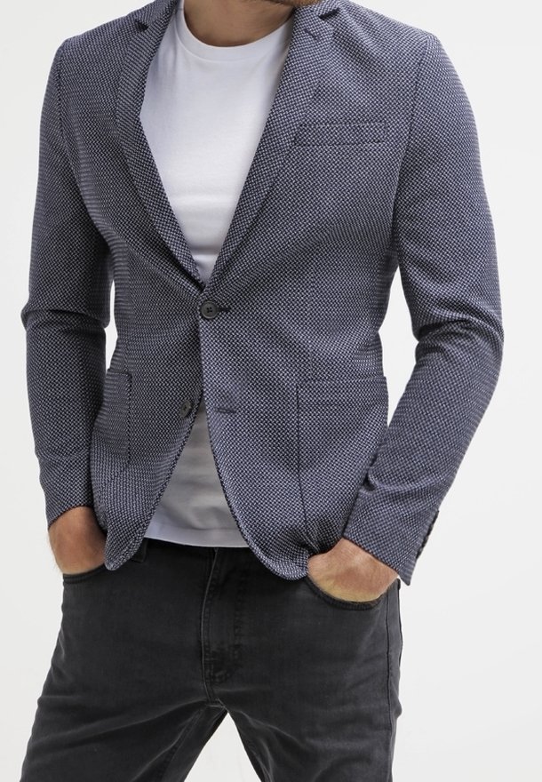 Mörkblå texturerad kavaj med en figursydd design, enfaldig knäppning, slagkrage och två framfickor, bärs över en vit skjorta.