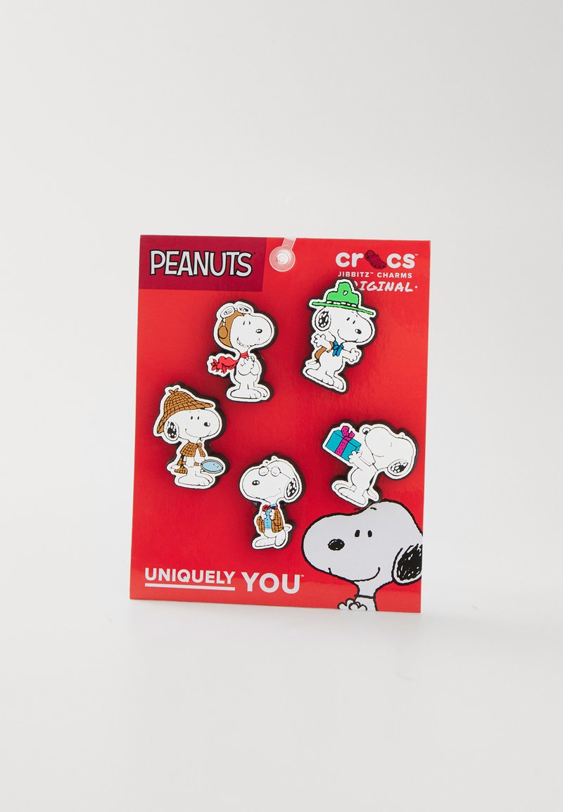 Cinq charms Jibbitz Crocs représentant des personnages de bande dessinée Snoopy dans différentes tenues sur une carte de fond rouge. Matériau : plastique, design coloré.