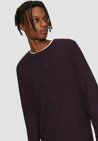 Langarm-Pullover aus dunkelviolettem strukturiertem Stoff mit einem weißen Rundhalskragen. Mit lockerer Passform und dezentem Seitenschlitz-Detail.